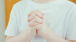 A child's hands folded in prayer, highlighting innocence and spirituality.