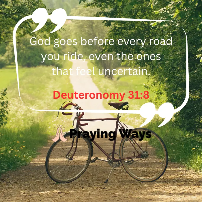 A vintage bicycle parked on a quiet dirt path surrounded by green trees, featuring a quote overlay that reads, "God goes before every road you ride, even the ones that feel uncertain. Deuteronomy 31:8" with the Praying Ways logo.