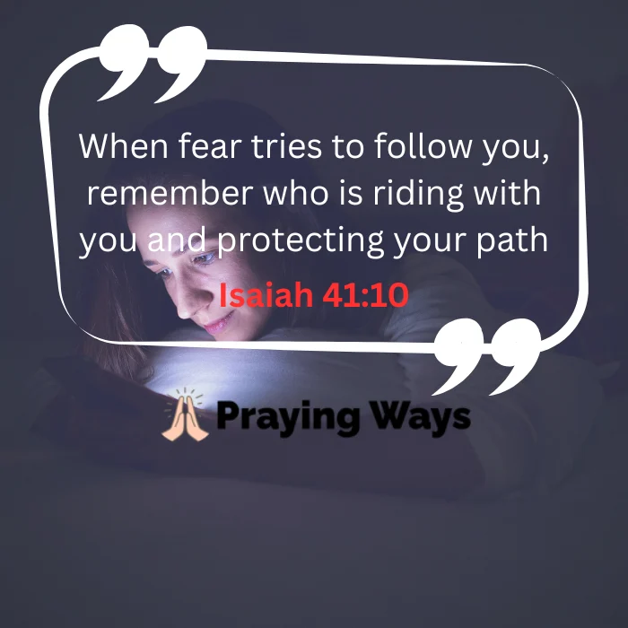 An overhead shot of a woman lying in bed at night, her face illuminated by the soft glow of her smartphone screen. Overlaid on the image within a white quote bubble is the text: "When fear tries to follow you, remember who is riding with you and protecting your path" followed by "Isaiah 41:10" in a bold red font.